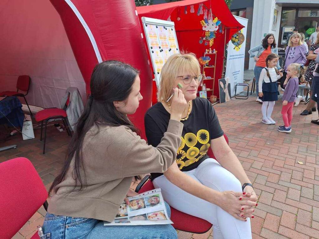 Visažistė piešia Lietuvos trispalvę ant Romos Janušonienės skruosto